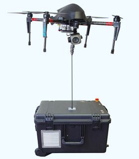 Tethered Drohne mit Kamera im Schwebeflug über Bodenstation mit Strom- und Datenkabel